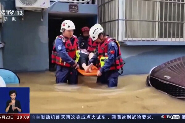 In this image taken from video footage run by China's CCTV, rescuers evacuate a resident following a flood in a village in eastern China's Zhejiang province on Sunday, July 23, 2023. Floods caused by heavy rain hit eastern China, leaving at least five dead and three missing while over 1,500 people were evacuated, state media reported on Sunday. (CCTV via AP)