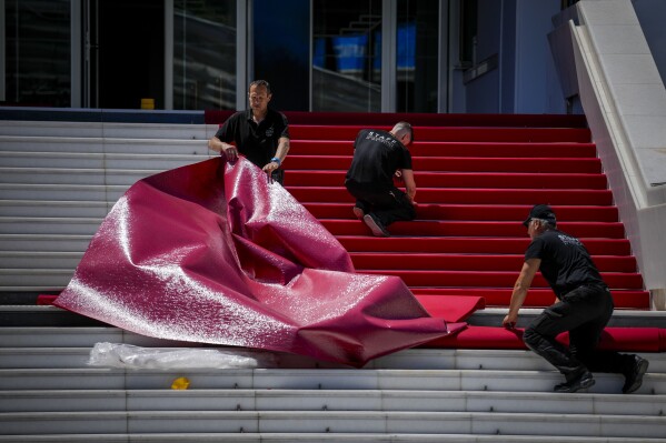 Os trabalhadores do festival estendem o tapete vermelho durante os preparativos para o 77º Festival Internacional de Cinema, Cannes, sul da França, segunda-feira, 13 de maio de 2024. O Festival de Cinema de Cannes acontece de 14 a 25 de maio de 2024. (AP Photo/Andreea Alexandru)