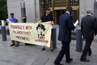 FILE - In this Monday, May 14, 2012, file photo, protesters stand in front of the federal courthouse during the arraignment of hacker Jeremy Hammond, in New York. Hammond, who is serving a 10-year prison sentence for breaking into computer systems of security firms and law-enforcement agencies, will serve out the remainder of his term in a Chicago halfway house, a U.S. Bureau of Prison spokesman said Wednesday, Nov. 18, 2020. (AP Photo/Seth Wenig, File)