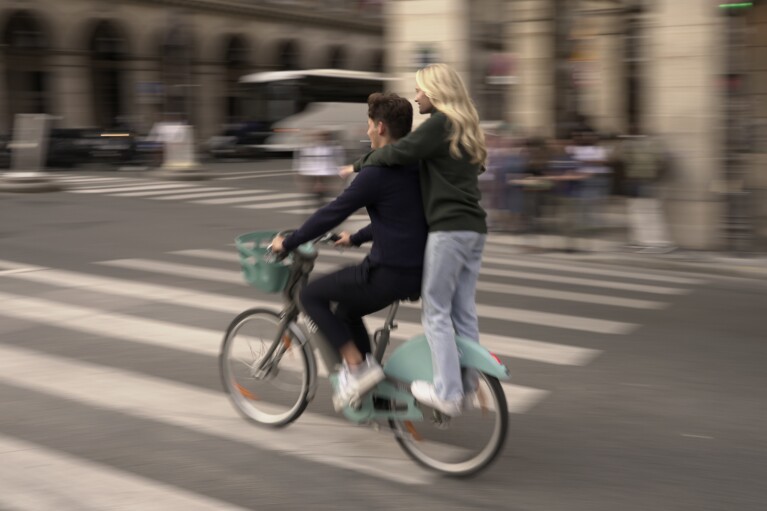 Youths ride on a bicycle in Paris, Wednesday, Sept. 13, 2023. Years of efforts to turn car-congested Paris into a more bike-friendly city are paying off ahead of the 2024 Olympics, with increasing numbers of people using the French capital's growing network of cycle lanes. (AP Photo/John Leicester)