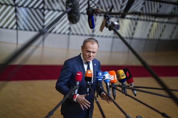 Poland's Prime Minister Donald Tusk talks to journalists as he arrives for an EU-Western Balkans summit at the European Council building in Brussels, Wednesday, Dec. 13, 2023. European Union and Western Balkans leaders meet in Brussels Wednesday to discuss political and policy engagement, economic foundations and the impact of Russian aggression against Ukraine. (AP Photo/Virginia Mayo)