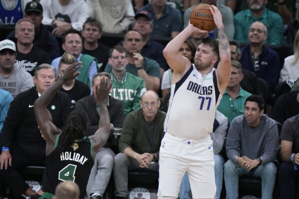 Dallas Mavericks guard Luka Doncic (77) looks to shoot over Boston Celtics guard Jrue Holiday (4) during the first half of Game 2 of the NBA Finals basketball series, Sunday, June 9, 2024, in Boston. (AP Photo/Steven Senne)