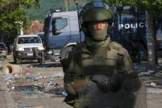 Soldados de la KFOR, la fuerza de paz de la OTAN, y policías de Kosovo protegen un edificio municipal tras los choques entre personas de etnia serbias y tropas de KFOR, en Zvecan, Kosovo, el martes 30 de mayo de 2023. (AP Foto/Dejan Simicevic)
