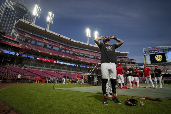 Cincinnati Reds' Jonathan India uses special glasses to watch the sun during a solar eclipse before a baseball game against the Milwaukee Brewers in Cincinnati, Monday, April 8, 2024. (AP Photo/Aaron Doster)