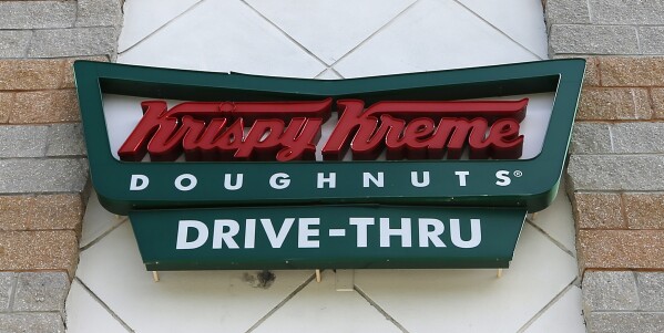 FILE - A Krispy Kreme Doughnuts sign is shown on Aug. 11, 2017, in Miami. More and more businesses are taking advantage of the total solar eclipse set to dim skies across North America on Monday, April 8, 2024. In the snacks department alone, Krispy Kreme is teaming up with Oreo to sell a limited doughnut-cookie creation. Sonic Drive-In is selling a “Blackout Slush Float.” (AP Photo/Alan Diaz, File)