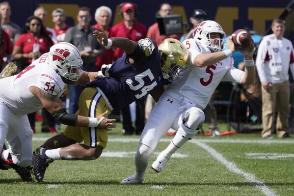 Wisconsin quarterback Graham Mertz (5) makes a two-handed pass to avoid the pressure from Notre Dame defensive lineman Jacob Lacey after Lacey got past lineman Kayden Lyles during the first half of an NCAA college football game Saturday, Sept. 25, 2021, in Chicago. (AP Photo/Charles Rex Arbogast)