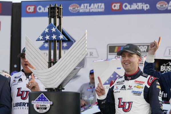 William Byron (24) poses with the trophy after winning a NASCAR Cup Series auto race at Atlanta Motor Speedway in Hampton, Ga., Sunday, March 20, 2022. (AP Photo/John Bazemore)