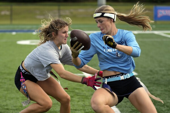 Ashlea Klam, 19, right, tries to evade a defender during a training session for her flag football team at Keiser University in West Palm Beach, Fla., Thursday, Nov. 30, 2023. The no-contact sport featuring plenty of offensive action has really been on the rise for a while, with girls-specific teams and leagues springing up from coast to coast. (AP Photo/Rebecca Blackwell)