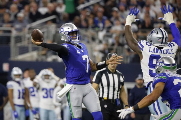 Seattle Seahawks quarterback Geno Smith (7) throws a touchdown pass to DK Metcalf, not pictured, under pressure from Dallas Cowboys defensive end DeMarcus Lawrence (90) in the second half of an NFL football game in Arlington, Texas, Thursday, Nov. 30, 2023. (APPhoto/Michael Ainsworth)
