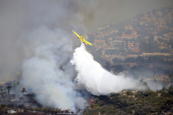 An aircraft drops water over a fire in Apesia, a semi-mountainous village near Limassol, southwestern Cyprus, Monday, Aug. 7, 2023. Greece on Monday dispatched two Canadair fire-fighting aircraft after a call for assistance from fellow European Union member Cyprus to help fight a blaze that has scorched miles of mountainous terrain. (AP Photo/Philippos Christou)