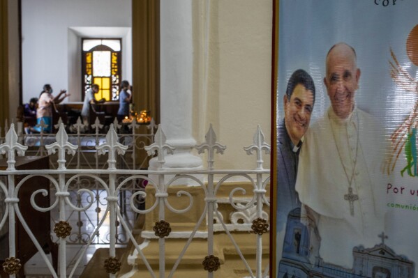 FILE - A poster featuring Bishop Rolando Alvarez and Pope Francis hangs inside the Cathedral in Matagalpa, Nicaragua, Aug. 19, 2022. Nicaragua has released and sent 12 Roman Catholic priests jailed on a variety of charges to Rome following an agreement reached with the Vatican, the Nicaraguan government said in a statement late Wednesday, Oct. 18, 2023. Bishop Álvarez was not among the names of the priests released. (AP Photo/Inti Ocon, File)