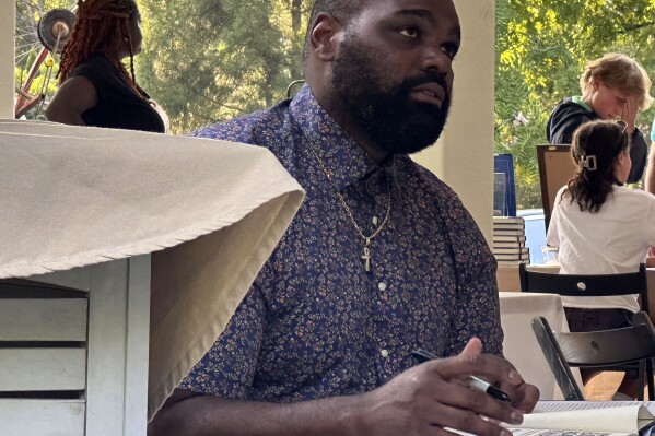 Former NFL football player Michael Oher, whose story became the inspiration for the Oscar-nominated movie “The Blind Side,” signs books at an event for his new memoir at a store in Baltimore, Monday, Aug. 21, 2023. Last week, Oher sued Sean and Leah Anne Tuohy to lift his conservatorship with them. (AP Photo/Stephen Whyno)