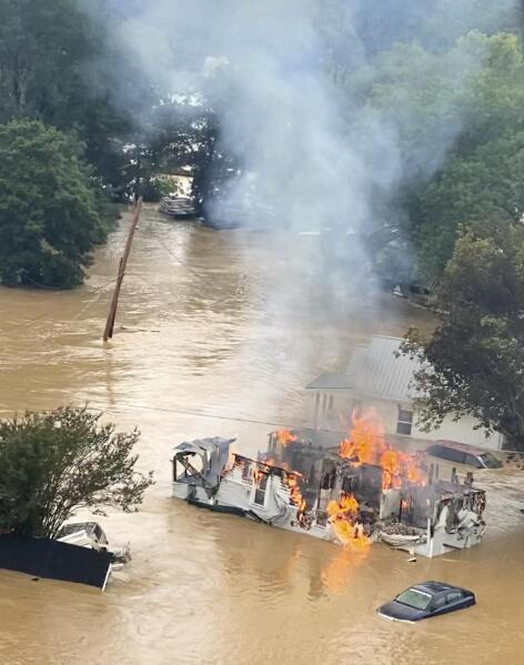 This image taken from video provided by co-pilot Melody Among, a home burns following flooding, Saturday, Aug. 21, 2021 in Waverly, Tenn. Helicopter pilot Joel Boyers, who co-owns Helistar Aviation, said he ended up rescuing 17 people that day. He’s proud of that, but said he’s the one who should be thanking them. (Melody Among via AP)
