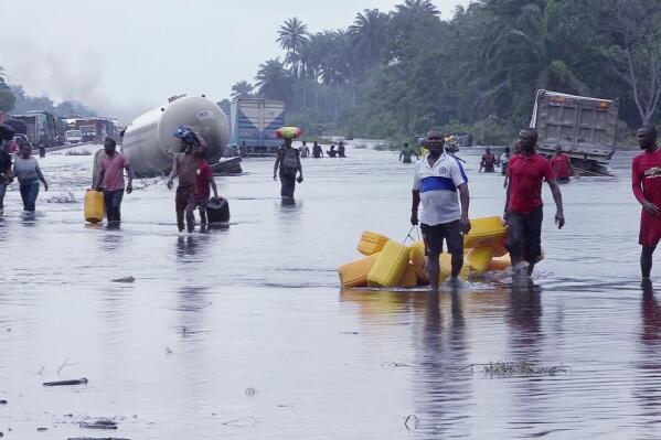 FILE- People wade through flooded roads in Bayelsa, Nigeria, Oct. 20, 2022. Climate change is to blame for the deadliest yet heavy rains and flooding that swamped Nigeria, Niger, Chad, and the neighboring Sahel region between the months of June and October leaving more than 800 people dead. (AP Photo/Reed Joshua, File)