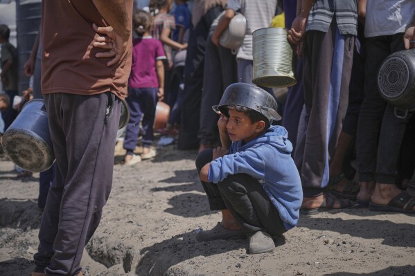 A boy holds an empty pot over his head as he waits for donated food at a community kitchen in Khan Younis, in the southern Gaza Strip, Friday, May 9, 2025. (AP Photo/Abdel Kareem Hana)