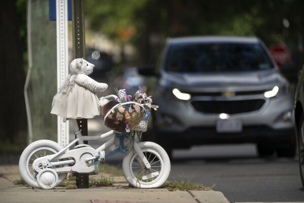 A vehicle drives past a memorial for 5-year-old Allie Hart, who was struck and killed in 2021 by a driver while riding her bicycle in a crosswalk, Monday, Sept. 11, 2023, in Washington. (AP Photo/Mark Schiefelbein)