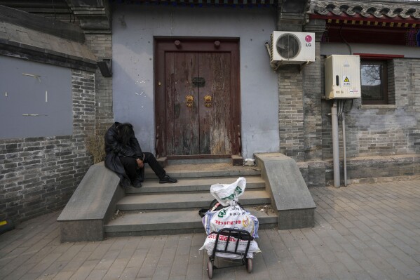 A man rests on the steps of a house in Beijing, China, Wednesday, April 3, 2024. (AP Photo/Tatan Syuflana)
