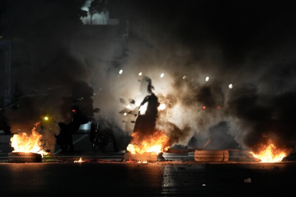 The shadow of a motorcyclist beams through a barricade on Bolivar Avenue in Caracas, Venezuela, Monday, July 29, 2024, the day after the presidential election. (AP Photo/Matias Delacroix)