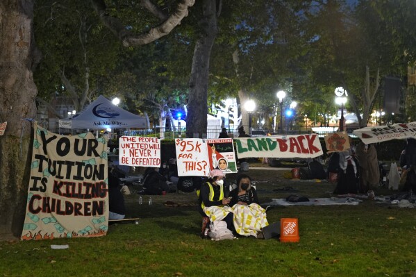 Persone fanno la guardia fuori da un accampamento allestito da manifestanti filo-palestinesi nel campus della University of Southern California a Los Angeles, sabato 4 maggio 2024.  (AP Photo/Ryan Sun)