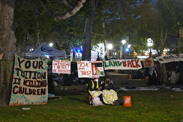 Menschen stehen Wache vor einem von pro-palästinensischen Demonstranten errichteten Lager auf dem Campus der University of Southern California in Los Angeles, Samstag, 4. Mai 2024.  (AP Photo/Ryan Sun)