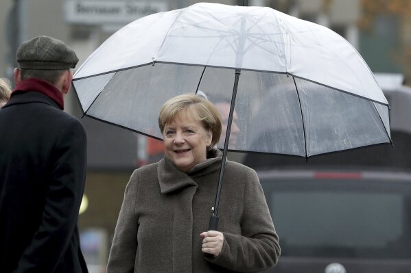German Chancellor Angela Merkel holds an umbrella as she arrives at the Berlin Wall Memorial in Berlin, Germany, Saturday, Nov. 9, 2019. (AP Photo/Michael Sohn, pool)