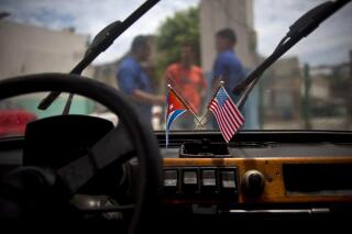 FILE - A Cuban and a U.S. flag hang from the windshield of a car parked in a garage in Havana, Cuba, Aug. 10, 2016. The U.N. General Assembly voted overwhelmingly on Nov. 3, 2022 to condemn the American economic embargo of Cuba for the 30th year. (AP Photo/Ramon Espinosa, File)
