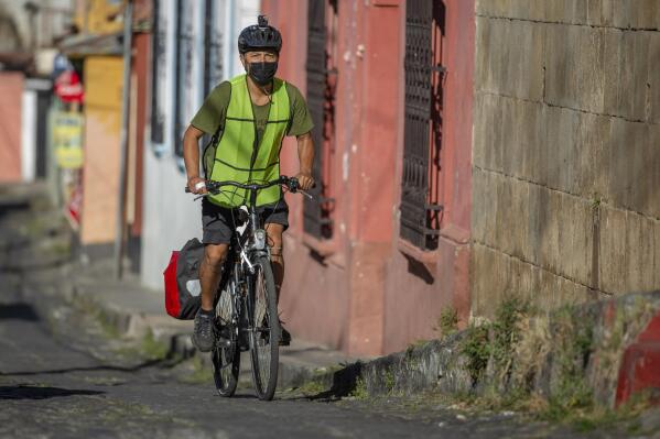 FILE - In this photo provided by Henning Sac, Bonifaz Diaz rides through the streets of Quetzaltenango, Guatemala, Saturday, Jan. 30, 2021. Diaz has pedaled thousands of miles to carry books that people can barter for bags of a cereal mix aimed at providing relief to families suffering chronic malnutrition. For more than a year, The Associated Press has been bringing you “One Good Thing” — stories highlighting good deeds done by individuals to brighten others' days during trying times.  (Henning Sac via AP)