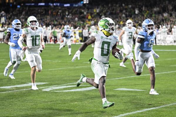 Oregon running back Bucky Irving (0) runs for a touchdown past North Carolina defensive back Lejond Cavazos (6) during the first half of the Holiday Bowl NCAA college football game Wednesday, Dec. 28, 2022, in San Diego. (AP Photo/Denis Poroy)