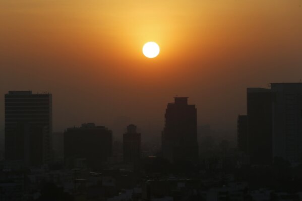 FILE - In this Thursday, Feb. 20, 2020 file photo, the sun rises amid smog during the dry season in Mexico City. Five years after a historic climate deal in Paris, world leaders are again meeting to increase their efforts to fight global warming. (AP Photo/Marco Ugarte)