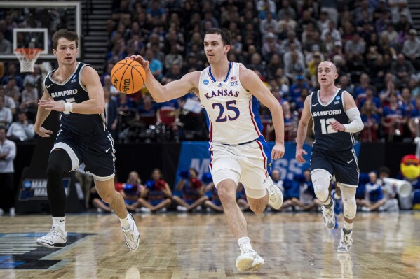 Kansas guard Nicolas Timberlake (25) brings the ball up-court between Samford forward Nathan Johnson, left, and guard Dallas Graziani (12) during the first half of a first-round college basketball game in the NCAA Tournament in Salt Lake City, Thursday, March 21, 2024. (AP Photo/Isaac Hale)