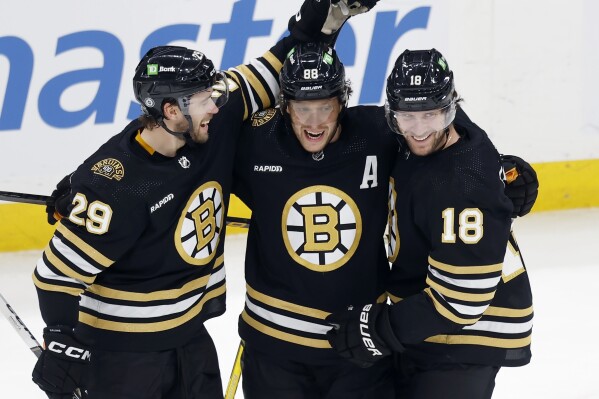 Boston Bruins' David Pastrnak (88) celebrates his second goal of the first period with Parker Wotherspoon (29) and Pavel Zacha (18) during an NHL hockey game against the Minnesota Wild, Tuesday, Dec. 19, 2023, in Boston. (AP Photo/Michael Dwyer)