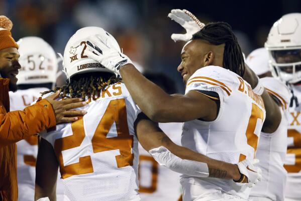 Texas running back Bijan Robinson (5) congratulates fellow running back Jonathon Brooks (24) after Brooks scored during the fourth quarter of an NCAA college football game against Kansas on Saturday, Nov. 19, 2022, in Lawrence, Kan. (AP Photo/Colin E. Braley)