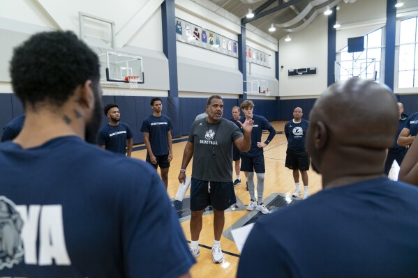 Georgetown head coach Ed Cooley (center) talks with players before the start of NCAA college basketball practice Thursday, Oct. 19, 2023, in Washington.  (AP Photo/Stephanie Scarbrough)