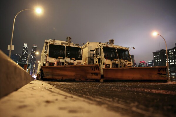 FILE — Sanitation trucks mounted with snow plows are parked on the west side of Manhattan in New York, Jan. 2, 2014. Parts of the Northeast were preparing Monday, Feb. 12, 2024, for a coastal storm that was expected to pack high winds and dump a foot or more of snow in some areas, leading to school closures, warnings against traveling by road and the possible disruption of flights.(AP Photo/Peter Morgan, File)