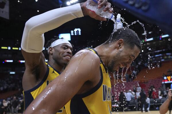 Indiana Pacers guard Buddy Hield, left, douses guard Tyrese Haliburton (0) after the team's NBA basketball game against the Miami Heat on Friday, Dec. 23, 2022, in Miami. Haliburton hit a 3-pointer with 2 seconds left. (AP Photo/Jim Rassol)