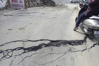 A motorist navigates his way through a crack on a road in Joshimath, India, Tuesday, Jan. 3, 2023. Authorities have stopped all construction activity and started shifting hundreds of people panicking after seeing a temple collapse and cracks in over 600 houses due to subsidence of land in a northern Indian hilly town, officials said on Saturday. (AP Photo)