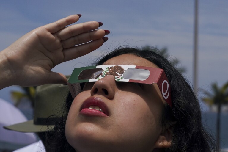 A woman uses special glasses to watch the total solar eclipse in Mazatlan, Mexico, Monday, April 8, 2024. (AP Photo/Fernando Llano)