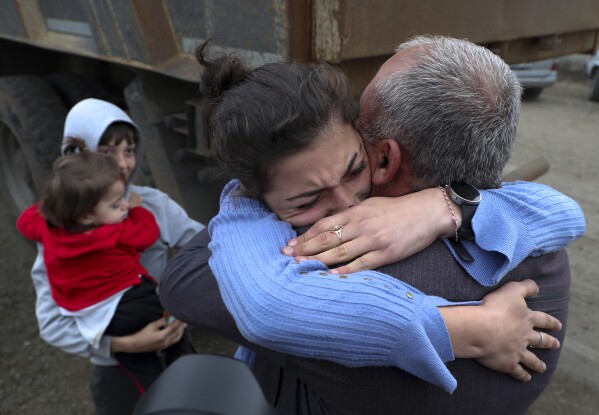 Ethnic Armenians who fled Nagorno-Karabakh embrace upon their arrival in Kornidzor, in Armenia's Syunik region, Tuesday, Sept. 26, 2023. (Stepan Poghosyan/PHOTOLURE Photo via AP)