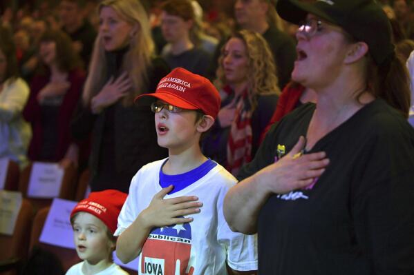 Members of the crowd stand for the National Anthem before former President Donald Trump speaks at a campaign event Monday, March 13, 2023, in Davenport, Iowa. (AP Photo/Ron Johnson)