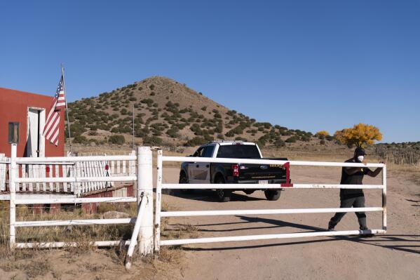 A security guard closes the gate after a Santa Fe County Sheriff's vehicle entered the Bonanza Creek Ranch in Santa Fe, N.M., Monday, Oct. 25, 2021. Production of the movie that Alec Baldwin was making when he shot and killed a cinematographer last week has been officially halted, but producers of the Western described the move as "a pause rather than an end." (AP Photo/Jae C. Hong)