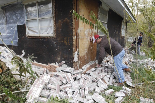FILE - Chad Devereaux works at cleaning up bricks that fell from three sides of his in-laws home in Sparks, Okla., Nov. 6, 2011, after two earthquakes hit the area in less than 24 hours. A couple of major earthquakes in Oklahoma, including a 5.1-magnitude quake on Feb. 2, 2024, have raised new concerns after years of a declining number of temblors. (AP Photo/Sue Ogrocki, File)