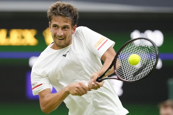 Vit Kopriva of the Czech Republic plays a backhand return to Serbia's Novak Djokovic during their first round match at the Wimbledon tennis championships in London, Tuesday, July 2, 2024. (AP Photo/Kirsty Wigglesworth)