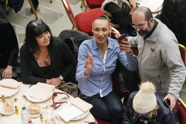 Don Andrea Conocchia, right, with members of a group of transgender women he accompanied at a lunch for the poor with Pope Francis, in the Paul VI Hall at the Vatican, Sunday, Nov. 19, 2023. Pope Francis is offering several hundred poor people, homeless, migrants, unemployed a lunch on Sunday as he celebrates the World Day of the Poor with a concrete gesture of charity in the spirit of his namesake, St. Francis of Assisi. (AP Photo/Andrew Medichini)