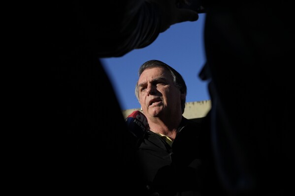 FILE - Brazil's former President Jair Bolsonaro speaks to the media upon arriving at the airport in Brasilia, Brazil, June 29, 2023. Brazil’s federal police on Friday, Aug. 11, 2023, alleged Bolsonaro received cash from the sale of two luxury watches he received as gifts from Saudi Arabia while in office. (AP Photo/Eraldo Peres, File)