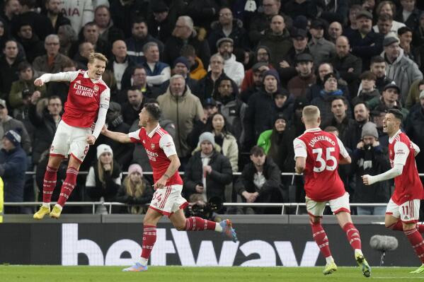 Arsenal players celebrate after Arsenal's Martin Odegaard, left, scored his side's second goal during the English Premier League soccer match between Tottenham Hotspur and Arsenal at the Tottenham Hotspur Stadium in London, England, Sunday, Jan. 15, 2023. (AP Photo/Frank Augstein)