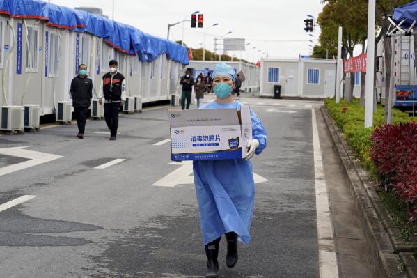 In this photo released by China's Xinhua News Agency, a worker carries a box of supplies at a makeshift hospital in Shanghai, China, Friday, April 15, 2022. Anti-virus controls that have shut down some of China's biggest cities and fueled public irritation are spreading as infections rise, hurting a weak economy and prompting warnings of possible global shockwaves. (Yang Youzong/Xinhua via AP)