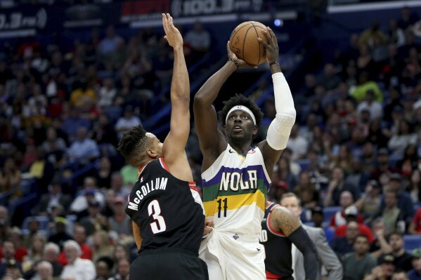 FILE  - In this Feb. 11, 2020, file photo, New Orleans Pelicans guard Jrue Holiday (11) shoots a basket as Portland Trail Blazers guard CJ McCollum (3) defends in the second half of an NBA basketball game in New Orleans. Jrue Holiday is being traded from New Orleans to Milwaukee, which is aiming to give two-time reigning NBA MVP Giannis Antetokounmpo the improved roster that he seeks with the decision on his supermax contract extension looming, a person with knowledge of the situation said Tuesday, Nov. 17, 2020. The Pelicans are getting Eric Bledsoe, George Hill and a package of future first-round draft picks from the Bucks, the person told The Associated Press. The person spoke on condition of anonymity because no deal had been finalized.  (AP Photo/Rusty Costanza, File)
