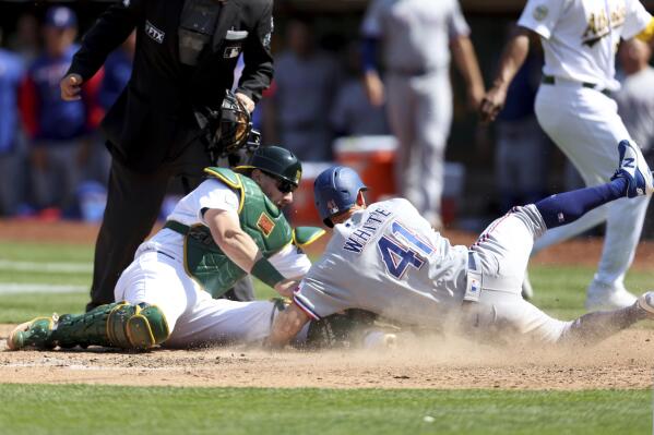Texas Rangers' Eli White (41) slides safely into home plate as Oakland Athletics catcher Sean Murphy, front left, applies the tag on a ball hit by Rangers' Brad Miller during the eighth inning of a baseball game in Oakland, Calif., Saturday, April 23, 2022. (AP Photo/Jed Jacobsohn)