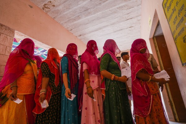 FILE- Women queue up to cast their vote during the second phase of polling in the six-week long national election in Barmer district, western Rajasthan state, India, April 26, 2024. Misinformation about India's election is surging online as the world's most populous country votes. The country has a huge online ecosystem, with the largest number of WhatsApp and YouTube users in the world. Nearly 1 billion people are eligible to vote in the multiphase election that ends next month.(AP Photo/Deepak Sharma, File)