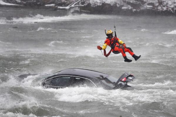 A U.S. Coast Guard diver is lowered from a hovering helicopter to pull a body from a submerged vehicle stuck in rushing rapids just yards from the brink of Niagara Falls, Wednesday, Dec. 8, 2021, in Niagara Falls, N.Y. (Sharon Cantillon/The Buffalo News via AP)